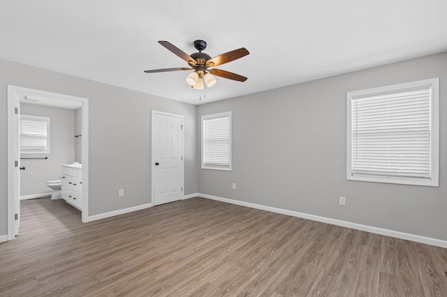 unfurnished bedroom with baseboards, a ceiling fan, light wood finished floors, and connected bathroom