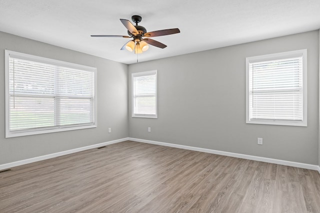spare room with baseboards, visible vents, ceiling fan, and light wood finished floors