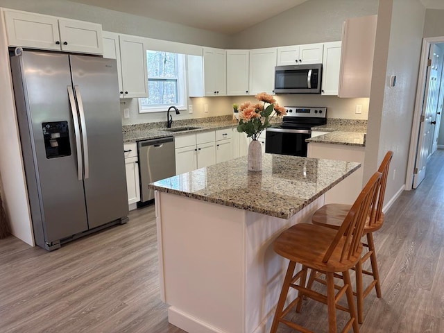 kitchen featuring a sink, appliances with stainless steel finishes, light wood finished floors, and white cabinetry