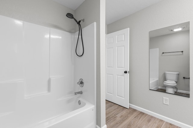 bathroom with baseboards,  shower combination, wood finished floors, and toilet