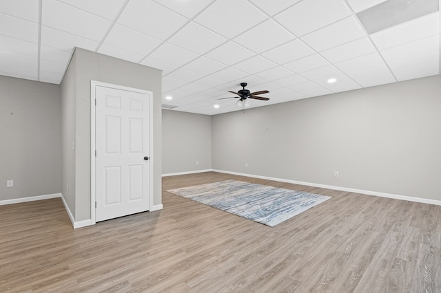 unfurnished living room featuring baseboards, a ceiling fan, a paneled ceiling, and light wood-style flooring
