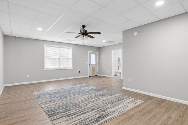unfurnished living room with baseboards, a ceiling fan, a drop ceiling, and wood finished floors