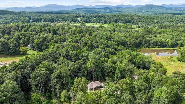drone / aerial view with a water and mountain view and a forest view