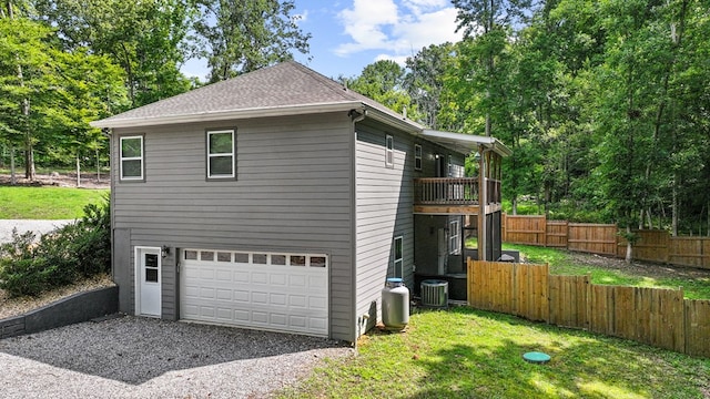 view of home's exterior featuring driveway, central air condition unit, fence, a balcony, and an attached garage