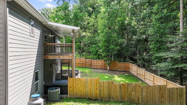 view of yard with a fenced backyard, central AC, and a wooden deck
