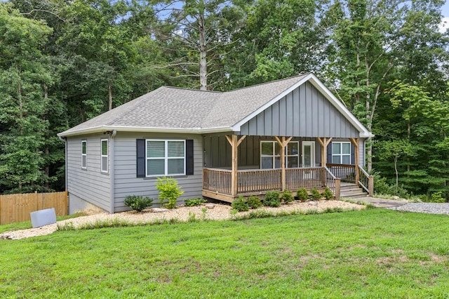 ranch-style house with board and batten siding, fence, a shingled roof, and a front lawn