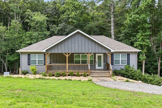 single story home with roof with shingles, a porch, and a front lawn