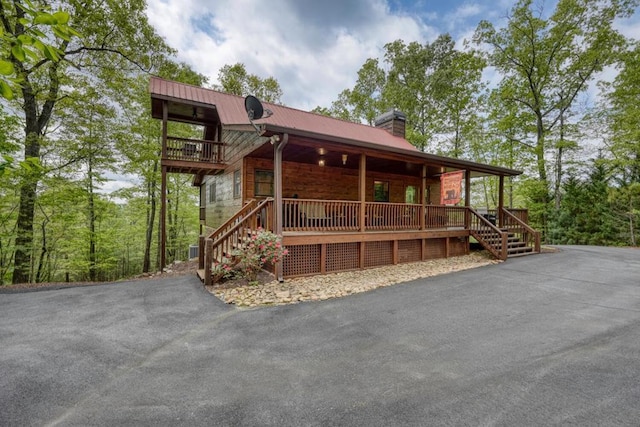 chalet / cabin featuring stairway, covered porch, a chimney, and metal roof