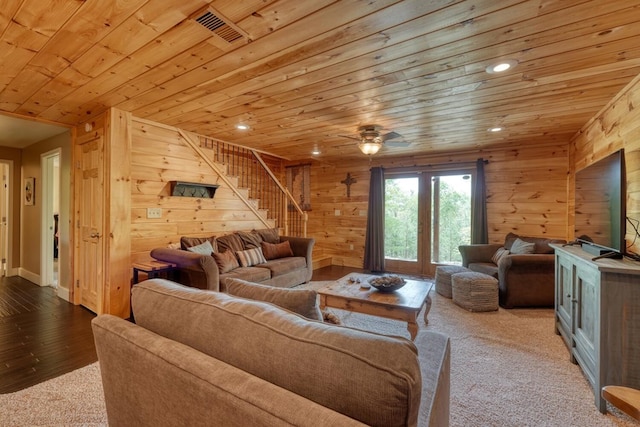 living room featuring stairway, wooden ceiling, wooden walls, and visible vents