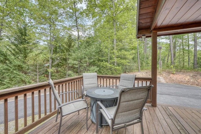 deck with outdoor dining area and a wooded view
