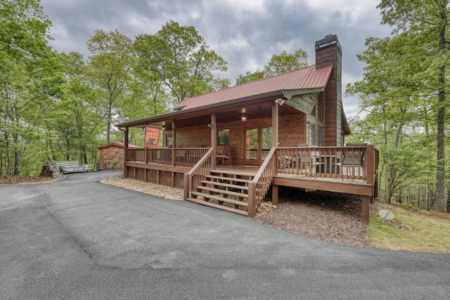 view of front of house featuring covered porch, a chimney, and metal roof