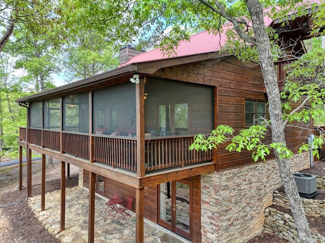 exterior space featuring a chimney, a sunroom, central AC, and a patio area
