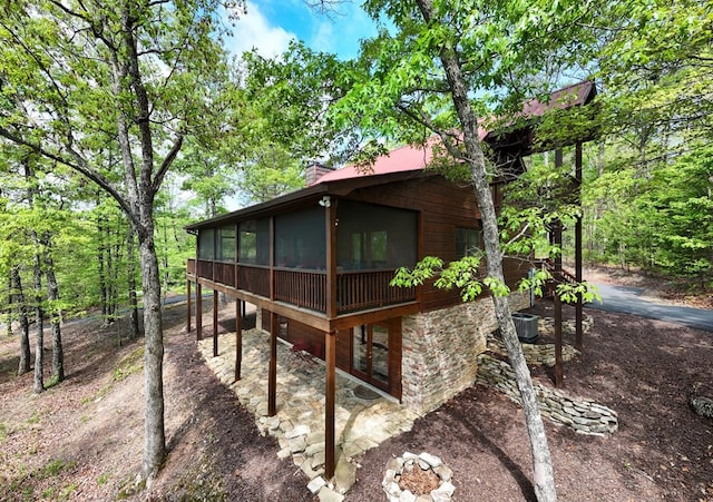 view of side of property with a patio, a chimney, and a sunroom
