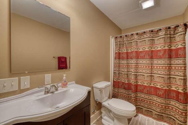 bathroom with toilet, curtained shower, lofted ceiling, and vanity