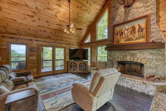 living area with wood-type flooring, a ceiling fan, wooden walls, and high vaulted ceiling