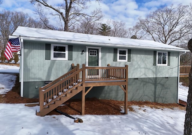 snow covered rear of property with a deck