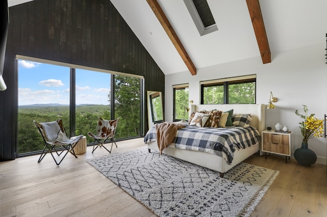 bedroom with light wood-type flooring, high vaulted ceiling, wooden walls, and beam ceiling