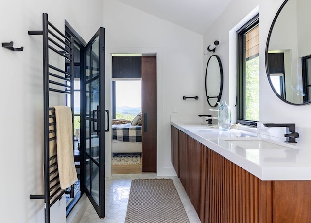 bathroom with tile patterned flooring, vaulted ceiling, and double sink vanity