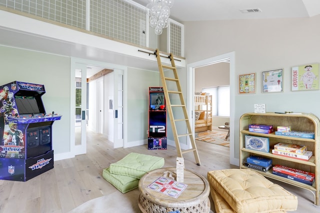 interior space featuring high vaulted ceiling, light hardwood / wood-style floors, and a chandelier