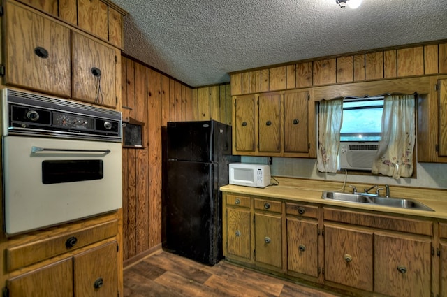 kitchen featuring dark wood-style floors, a sink, a textured ceiling, cooling unit, and white appliances