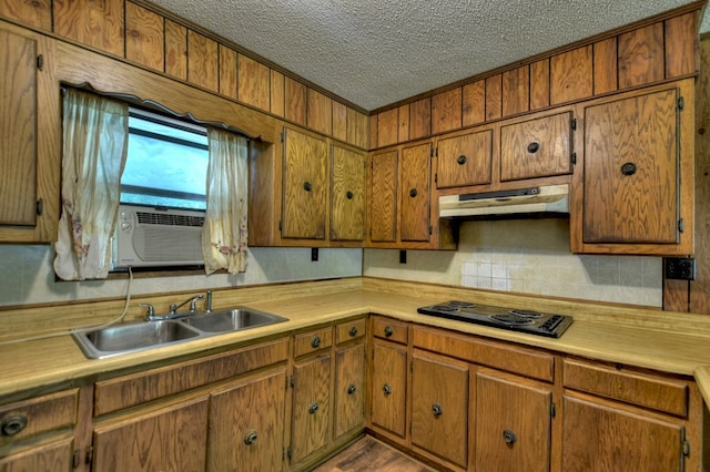 kitchen featuring light countertops, black electric stovetop, a sink, and under cabinet range hood