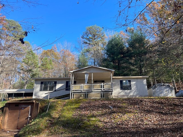 view of front of property featuring covered porch and a storage shed