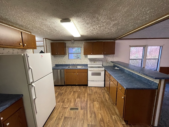 kitchen with a textured ceiling, hardwood / wood-style floors, a healthy amount of sunlight, and white appliances