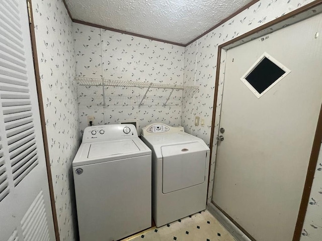 clothes washing area with washing machine and dryer, ornamental molding, and a textured ceiling