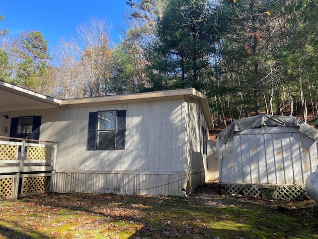 view of side of home featuring a storage shed and a deck