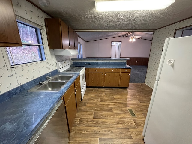 kitchen with dark wood-type flooring, sink, vaulted ceiling, a textured ceiling, and white appliances