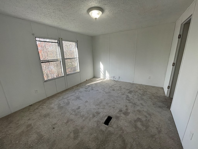 carpeted spare room featuring a textured ceiling