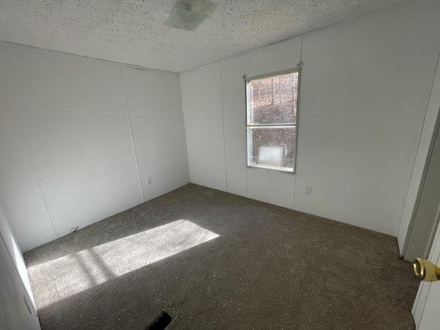 empty room featuring dark carpet and a textured ceiling