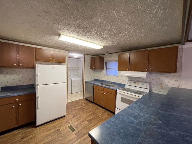 kitchen featuring sink, a textured ceiling, washing machine and clothes dryer, and white appliances