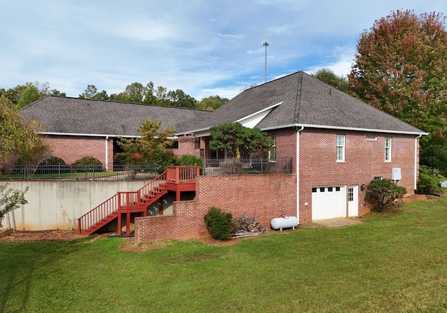 rear view of property with a lawn, a wooden deck, and a garage