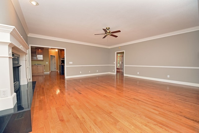 unfurnished living room with a tile fireplace, crown molding, and ceiling fan