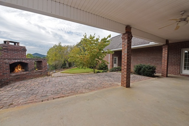 view of patio / terrace featuring a mountain view, an outdoor brick fireplace, and ceiling fan