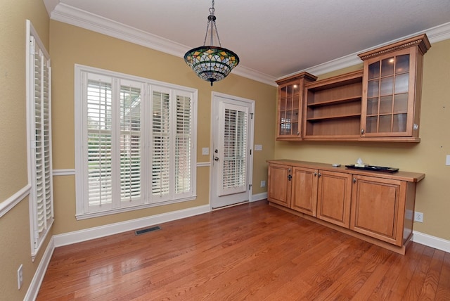 unfurnished dining area with crown molding, a notable chandelier, and hardwood / wood-style flooring