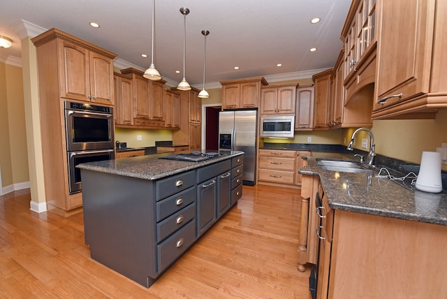 kitchen featuring a center island, sink, stainless steel appliances, dark stone counters, and decorative light fixtures