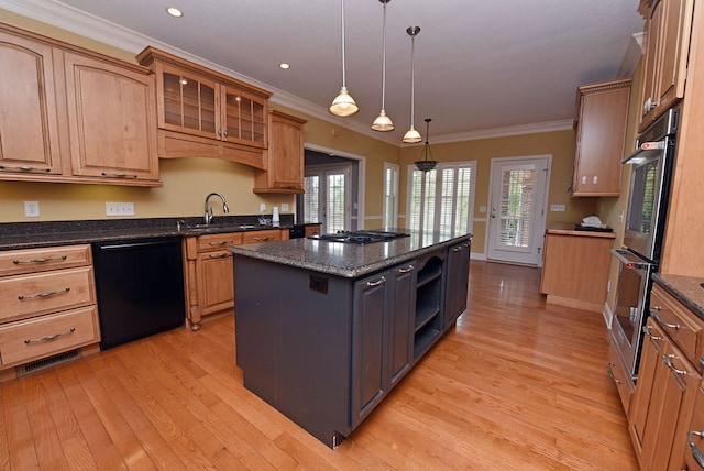 kitchen with dark stone countertops, appliances with stainless steel finishes, light wood-type flooring, a kitchen island, and ornamental molding