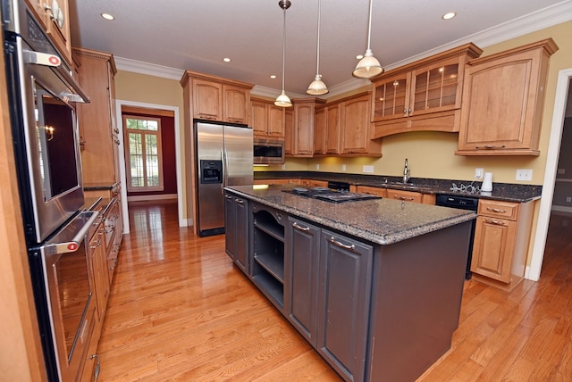 kitchen with dark stone counters, crown molding, black appliances, pendant lighting, and a center island