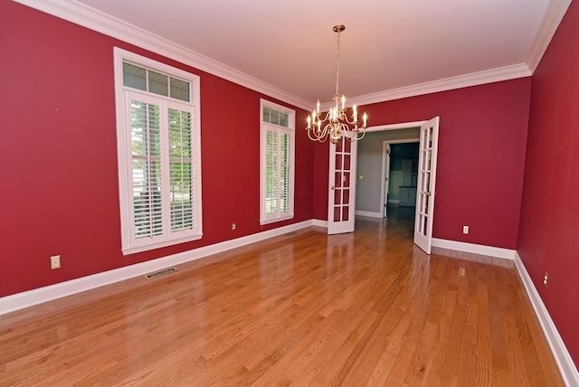 unfurnished dining area with a notable chandelier, wood-type flooring, crown molding, and french doors