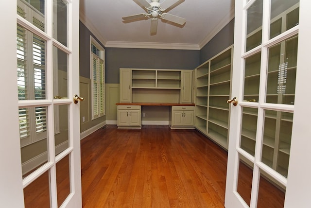 unfurnished office with french doors, ornamental molding, ceiling fan, wood-type flooring, and built in desk