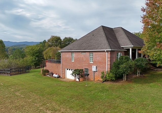 view of side of property with a mountain view, a yard, and a garage