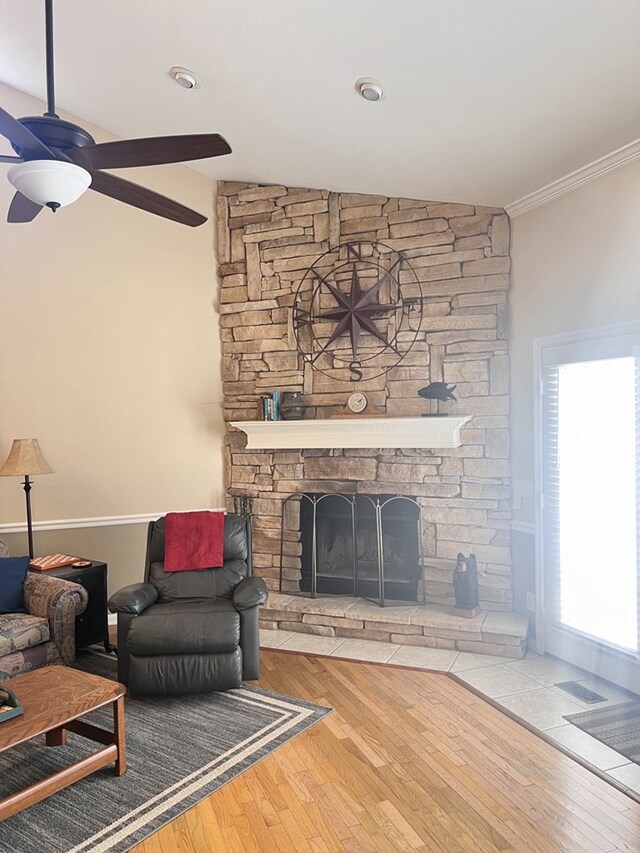 living room with a fireplace, crown molding, wood-type flooring, ceiling fan, and lofted ceiling