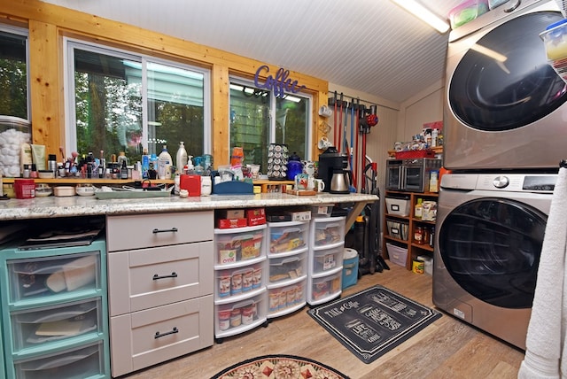 clothes washing area with laundry area, stacked washer and dryer, and wood finished floors
