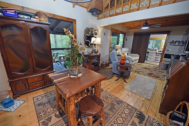 living area featuring a wealth of natural light, light wood-type flooring, a towering ceiling, and ceiling fan