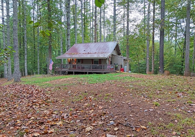 view of front facade with metal roof, a wooded view, and a wooden deck