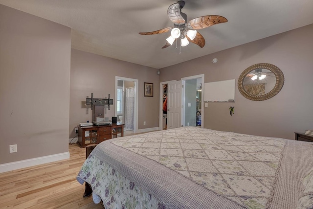 bedroom featuring ceiling fan, a spacious closet, and light hardwood / wood-style floors