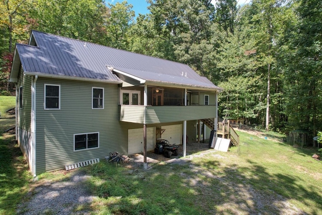 rear view of house featuring a garage, a sunroom, and a lawn