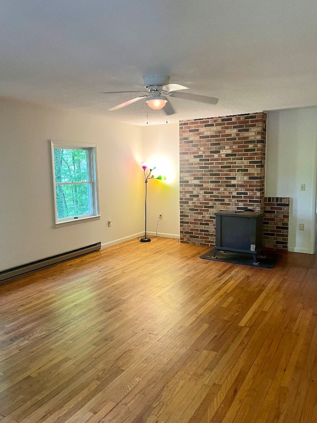 unfurnished living room featuring ceiling fan, a baseboard radiator, hardwood / wood-style floors, and a textured ceiling